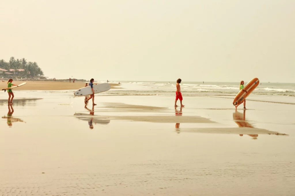 Group walking with surfboards on beach in Goa